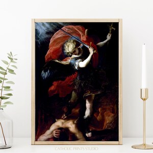 Peut inclure: Une impression d'art encadrée représentant une peinture classique d'un ange aux cheveux blonds, aux ailes sombres et à la cape rouge, tenant une épée et une croix au-dessus d'une silhouette. Le texte CATHOLIC PRINTS STUDIO est inscrit en bas.