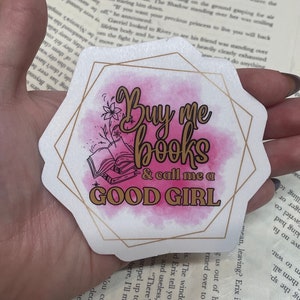 May include: A pink and gold sticker with a watercolor background and the text "Buy me books & call me a good girl".