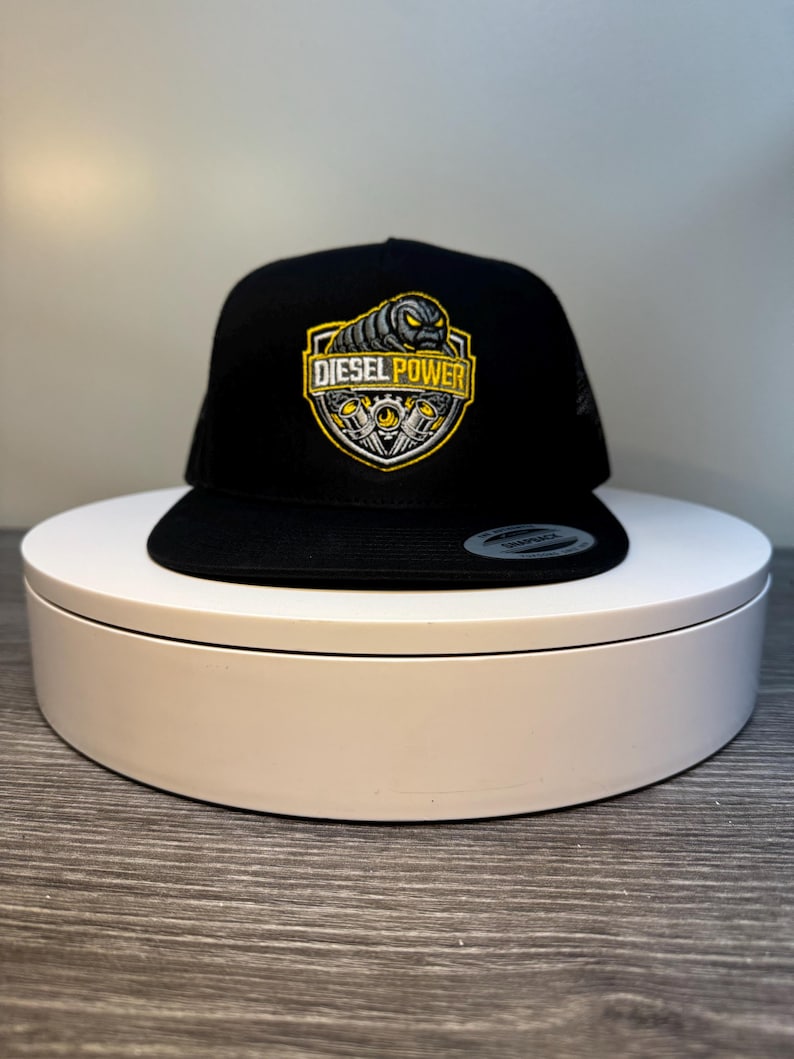 Pode incluir: Bon&eacute; de caminhoneiro preto com parte traseira em malha e aba reta. A frente apresenta um patch bordado amarelo e preto com "DIESEL POWER" e um gr&aacute;fico de motor.