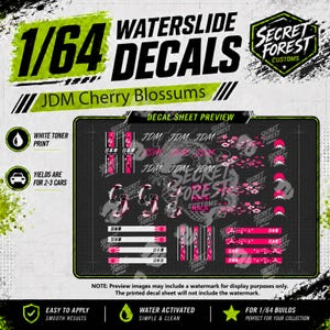 May include: A 1/64 scale waterslide decal sheet featuring JDM Cherry Blossoms designs. The sheet includes various pink and white floral patterns, Japanese text, and graphic elements on a dark background, designed for 1/64 scale model car builds.