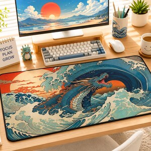 May include: A rectangular desk mat featuring a vibrant illustration of a blue dragon emerging from stylized ocean waves against a large orange sun. The design incorporates traditional artistic elements with deep blues, teals, and warm orange tones.