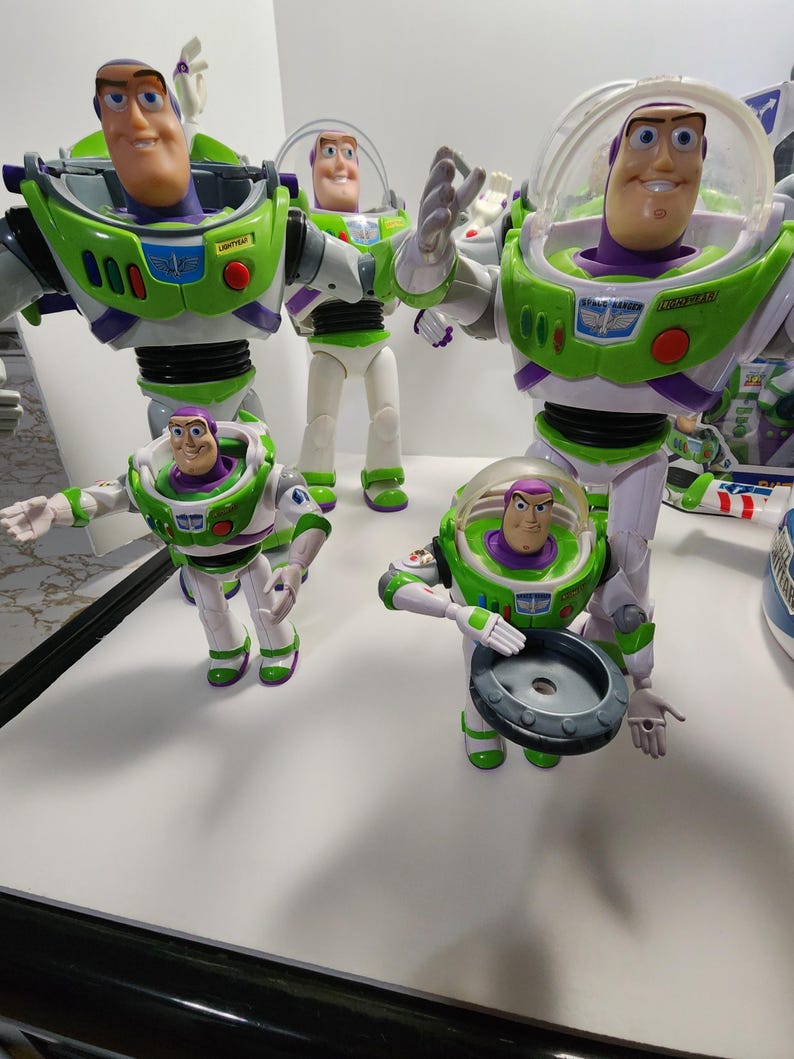 May include: Four different sized Buzz Lightyear action figures from the Toy Story franchise. The figures are all green, white, and purple with a space ranger design. The figures are all in different poses.