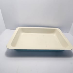 May include: Rectangular baking dish with a cream-colored interior and a light blue exterior. The dish has a slightly raised rim and is empty. The dish is made of a durable material and is suitable for baking.