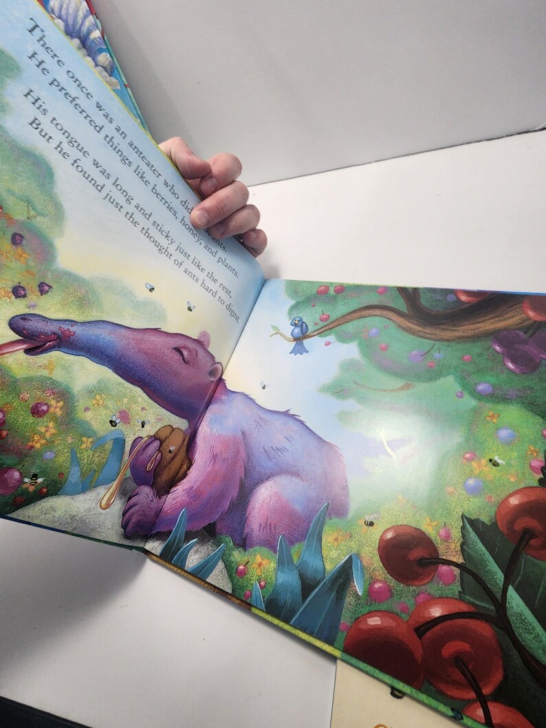 Puede incluir: Ilustraci&oacute;n de un libro infantil con un oso hormiguero morado con una larga lengua, rodeado de cerezas y flores. El texto dice: "&Eacute;rase una vez un oso hormiguero que... Prefer&iacute;a cosas como bayas, miel y plantas."