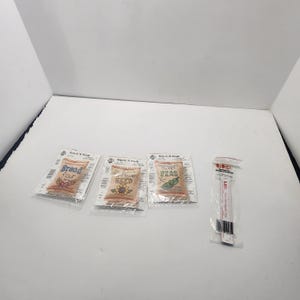 May include: Three Stitch 'N Stuff counted cross stitch kits featuring designs of bread flour, sunflower seed, and sweet peas, each in a clear plastic package. Beside them is a LKG magnetic ruler counter in a clear plastic sleeve.