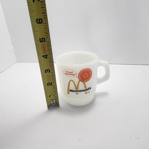 Puede incluir: Una taza de cer&aacute;mica blanca con un asa negra y el texto "But First, Coffee" en negro, con una fuente de estilo manuscrito. La taza est&aacute; sobre una superficie blanca.
