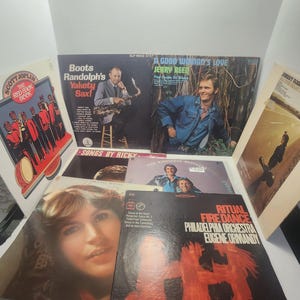 May include: A collection of vintage vinyl records featuring album covers with various artists and titles. The covers display images of musicians, album art, and text. Titles include "Boots Randolph's Yakety Sax!", "A Good Woman's Love", and "Ritual Fire Dance".