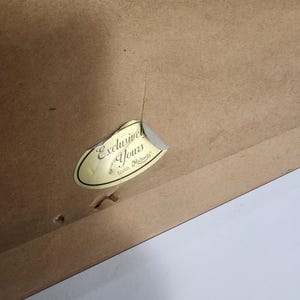 Peut inclure: Gros plan sur un cadre en bois marron avec un autocollant d&eacute;chir&eacute; indiquant "Exclusive Yours from Michaels". Le cadre pr&eacute;sente une fissure visible et plusieurs petits trous. Le fond est blanc.