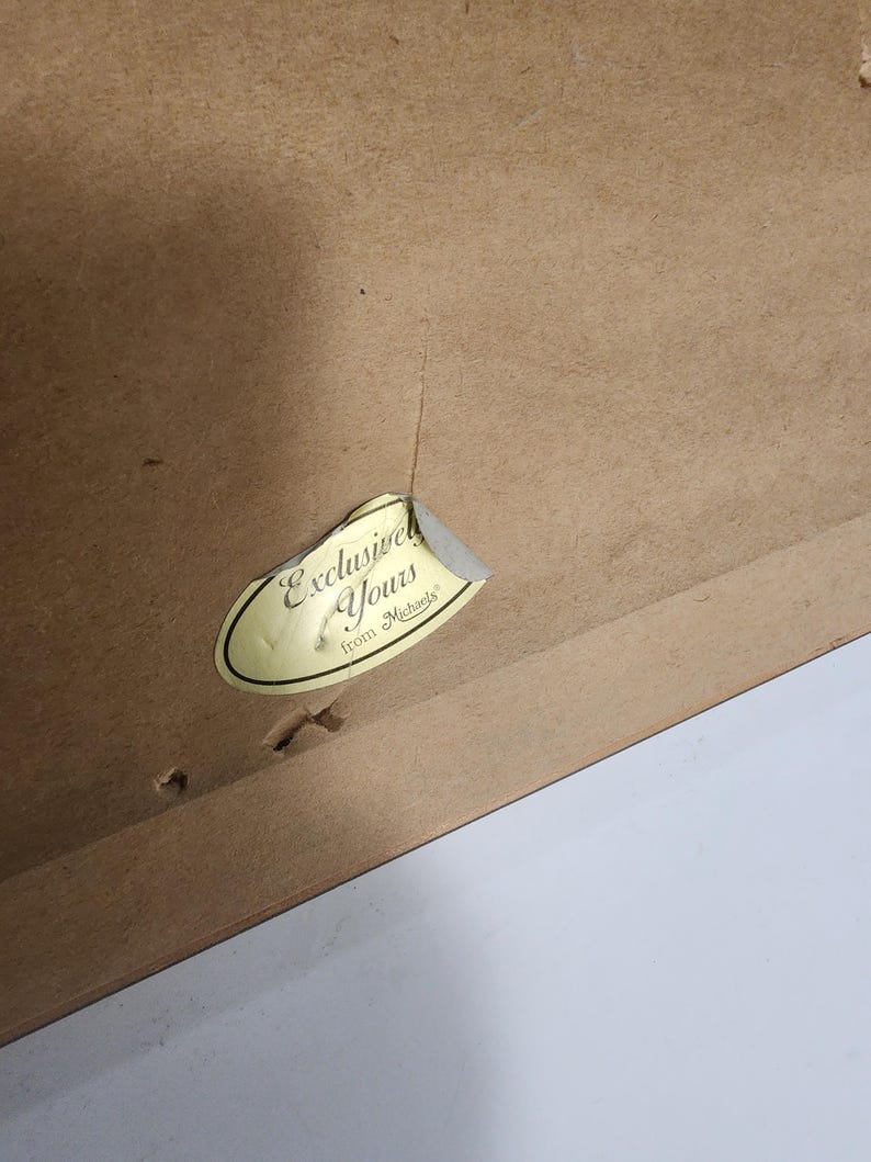 Peut inclure: Gros plan sur un cadre en bois marron avec un autocollant d&eacute;chir&eacute; indiquant "Exclusive Yours from Michaels". Le cadre pr&eacute;sente une fissure visible et plusieurs petits trous. Le fond est blanc.