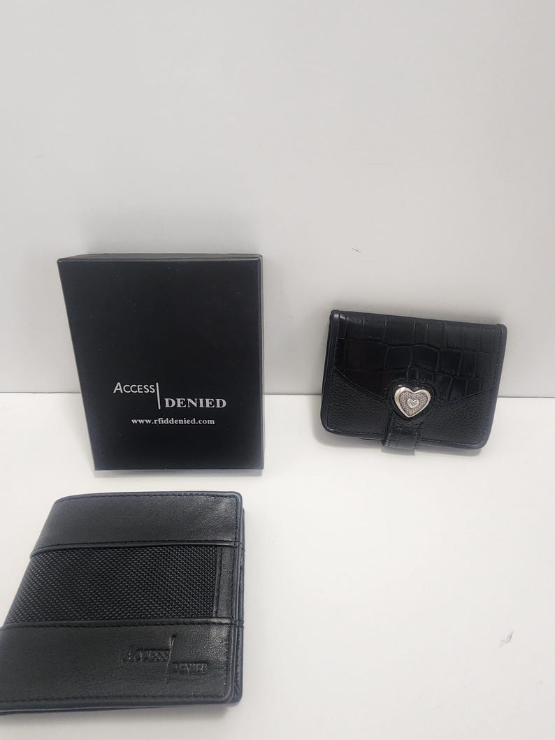 May include: Three black wallets and a black box are displayed against a white background. The box has the text "ACCESS DENIED" and the website address "www.rfiddenied.com". One wallet has a heart-shaped clasp.
