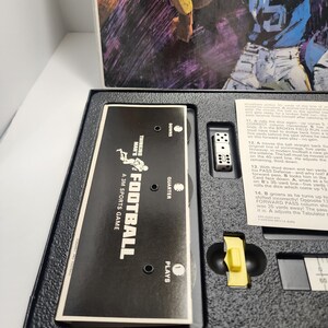 Peut inclure: Un jeu de football vintage 3M Thinking Man's dans une bo&icirc;te noire. Le plateau de jeu pr&eacute;sente un joueur de football courant avec le ballon. La bo&icirc;te comprend des d&eacute;s, un curseur et un plateau de jeu.