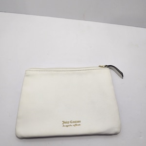 May include: A white leather clutch bag with a zip and a small black pull tab. The gold text "Juicy Couture Los Angeles California" is printed on the front.