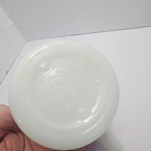 Puede incluir: Una taza blanca y opaca con base redondeada y asa. La base de la taza tiene el texto en relieve "Anchor Hocking" y "Made in U.S.A.". La taza est&aacute; limpia y parece estar en buen estado.