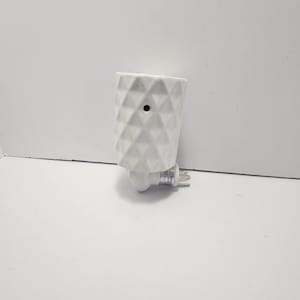 May include: A white ceramic plug-in wax warmer with a geometric diamond pattern. The warmer has a small black hole at the top and a standard UK plug. The product is designed for use with scented wax melts.
