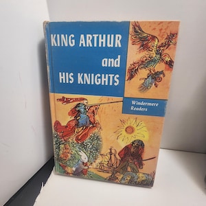 Puede incluir: Libro infantil vintage titulado "KING ARTHUR and HIS KNIGHTS" con una cubierta azul y naranja. La portada presenta ilustraciones de caballeros, un fénix y otras figuras. Parte de la serie Windermere Readers.