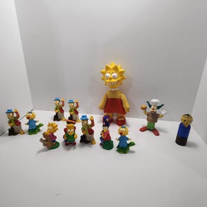 Może przedstawiać: Kolekcja figurek postaci z Simpsonów, w tym Bart, Lisa, Maggie i Krusty Klaun. Figurki są wykonane z plastiku i są jaskrawo kolorowe. Jest też większa figurka Lisy w czerwonej sukience.
