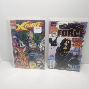 May include: Two X-Force comic books in plastic sleeves. The first comic features a group of characters in a colorful illustration with the title "X-Force". The second comic has a woman in a black outfit and the title "X-Force" with the text "Siron Lost in Silence".