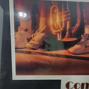 Peut inclure: Photographie encadr&eacute;e avec le texte "1995 Bix 7". L'image pr&eacute;sente une trompette et des baskets. Les baskets sont blanches avec des accents rouges. La photographie est dans un cadre noir.