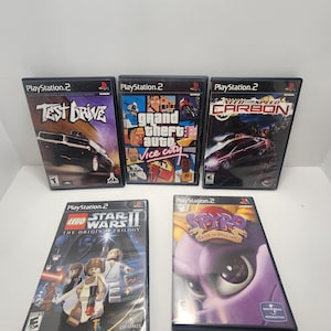 May include: Five PlayStation 2 video game cases. The cases are black with colourful covers. The games are Test Drive, Grand Theft Auto: Vice City, Need for Speed: Carbon, Lego Star Wars II: The Original Trilogy, and Spyro: Enter the Dragonfly.