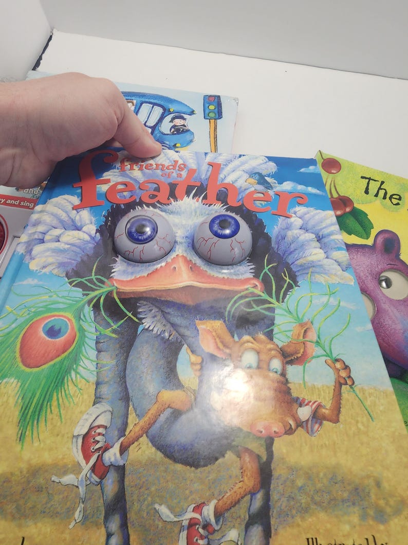 Puede incluir: Una pila de libros infantiles. El libro superior, titulado "Friends of a Feather", presenta una ilustraci&oacute;n de dibujos animados de una criatura con ojos grandes y saltones y un personaje parecido a un burro con zapatillas rojas.