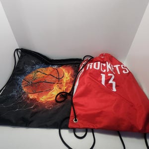 May include: Two drawstring bags. One is black with a basketball on fire design. The other is red with white text that says "ROCKETS 13".