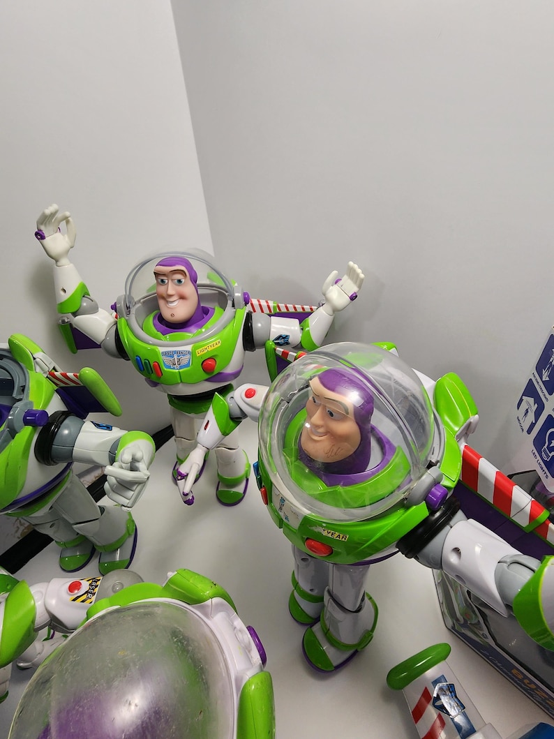 May include: Four Buzz Lightyear action figures from the Toy Story franchise. The figures are green, white, and purple with a clear plastic dome over the head. The figures have articulated arms and legs.