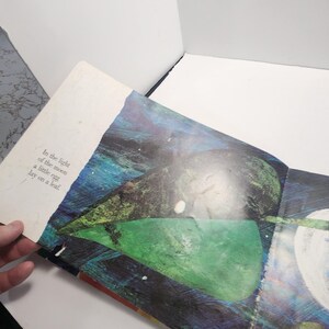 Puede incluir: Un libro abierto en una p&aacute;gina con una ilustraci&oacute;n colorida de una hoja verde, azul y amarilla con un huevo blanco en la parte superior. El texto en la p&aacute;gina dice "In the light of the moon a little egg lay on a leaf."