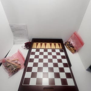 May include: A wooden game board with a chessboard on one side and a backgammon board on the other. The board is closed and has a brown finish. There are game pieces in plastic bags next to the board.