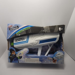 May include: A white and blue plastic toy Snowball Blaster in its original packaging. The box features the text "Arctic Force" and "Snowball Blaster". The packaging also includes a vinyl target. Recommended for ages 8 and up.