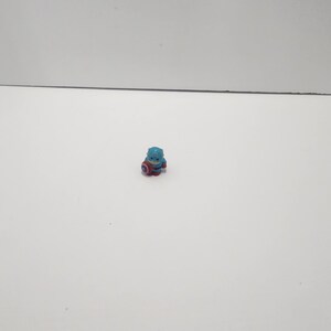 May include: A small blue and red plastic figurine of Captain America, holding his shield.