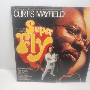 May include: Vintage vinyl record album cover for the soundtrack of "Super Fly" by Curtis Mayfield. The cover features a portrait of a man wearing glasses, and a man in a white suit. The album title is in large yellow and red letters.