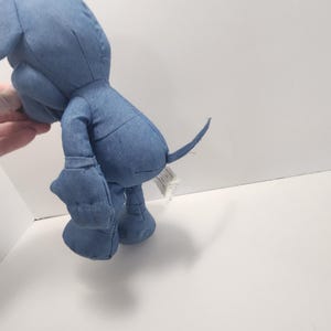 Puede incluir: Un peluche de elefante de mezclilla azul. El animal de peluche tiene patas grandes y redondeadas, una larga trompa y una peque&ntilde;a cola. El elefante est&aacute; hecho de tela de mezclilla azul claro y tiene costuras cosidas.