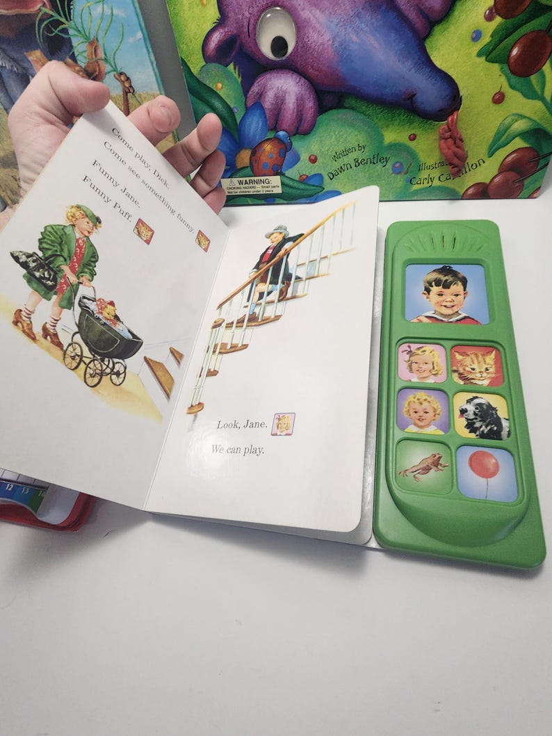 Puede incluir: Un libro infantil abierto con ilustraciones y texto, sostenido por una mano. El texto dice "Come play, Dick. Come see something funny. Funny Jane, Funny Puff." Un juguete verde con im&aacute;genes de ni&ntilde;os y animales est&aacute; al lado del libro.