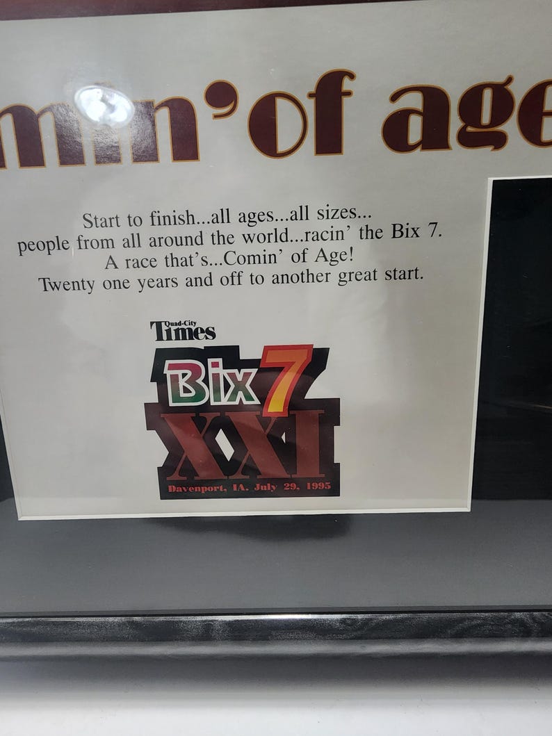 Peut inclure: Impression encadr&eacute;e avec le texte "men of age" en marron. L'impression comprend du texte sur la course Bix 7, avec le nom de la course et la date, le 29 juillet 1995, bien en &eacute;vidence.