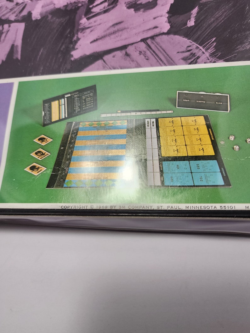 Peut inclure: Un plateau de jeu avec une grille de cases, une feuille de score et des d&eacute;s. Le plateau de jeu est vert et bleu, et la feuille de score est jaune. Les d&eacute;s sont blancs. Le jeu s'appelle "Le Jeu de la Vie".