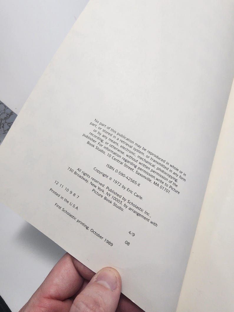 Puede incluir: La contraportada de un libro titulado "La Oruga Muy Hambrienta" de Eric Carle. La informaci&oacute;n de copyright incluye el a&ntilde;o 1972, el editor Scholastic Inc. y el ISBN 0-590-42565-X.