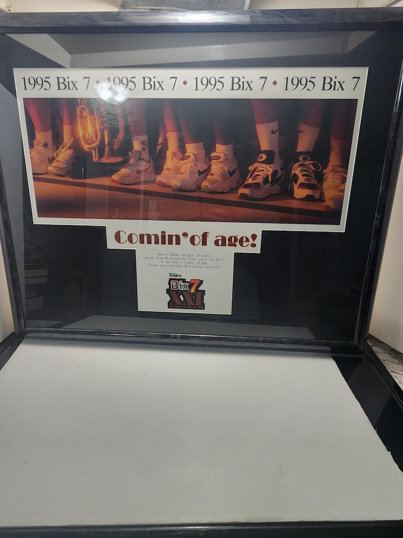 Peut inclure: Impression encadr&eacute;e avec le texte "1995 Bix 7" en haut et la phrase "Comin' of age!" en dessous. L'image montre des personnes portant des baskets. Le logo Bix est &eacute;galement visible. Le cadre est noir.