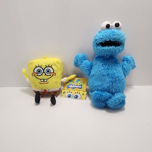 May include: A blue plush Cookie Monster toy and a yellow plush Spongebob Squarepants toy. Both toys are sitting on a white surface.