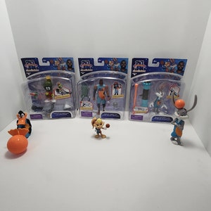 May include: A set of four Space Jam: A New Legacy action figures. The figures include Bugs Bunny, Daffy Duck, Lola Bunny, and LeBron James. The figures are packaged in clear plastic boxes with colorful backgrounds. The boxes feature the Space Jam: A New Legacy logo and the characters' names.