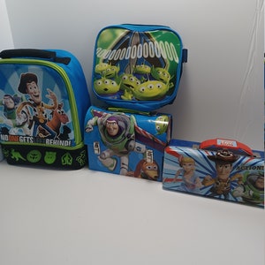 Può includere: Diversi portapranzo blu e uno zaino con personaggi del film d'animazione "Toy Story". I portapranzo presentano immagini di Buzz Lightyear, Woody e gli omini verdi. Lo zaino ha la scritta "NO ONE GETS LEFT BEHIND!"