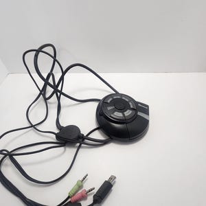 May include: A black circular headset control with a USB connector and three audio jacks. The control has multiple buttons and a dial.