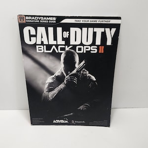 May include: A black and white guide for the video game Call of Duty: Black Ops II. The cover features a silhouetted figure holding a gun, with the game's title prominently displayed. The BradyGames logo is visible.