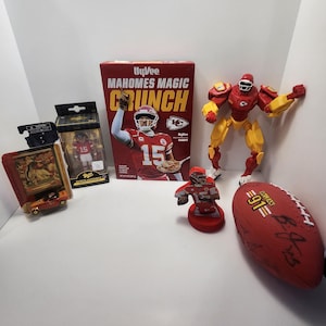 Op de afbeelding: Een verzameling Kansas City Chiefs memorabilia, waaronder een doos Mahomes Magic Crunch-ontbijtgranen, een voetbal, een beeldje van Patrick Mahomes en een klein ingelijst plaatje van een auto.
