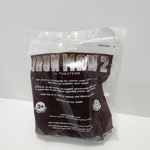 May include: A brown plastic bag with the words "Iron Man 2" in white letters. The bag is for a toy and has a warning that it is not intended for children under 3 years of age. The bag also has a Burger King logo and the text "www.ClubBK.com".