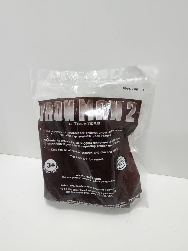 May include: A brown plastic bag with the words "Iron Man 2" in white letters. The bag is for a toy and has a warning that it is not intended for children under 3 years of age. The bag also has a Burger King logo and the text "www.ClubBK.com".