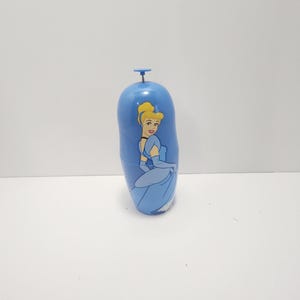 May include: A blue, cylindrical water bottle with a cartoon image of Cinderella in her ball gown. The bottle has a blue cap and a white base. The design is a classic Disney theme.