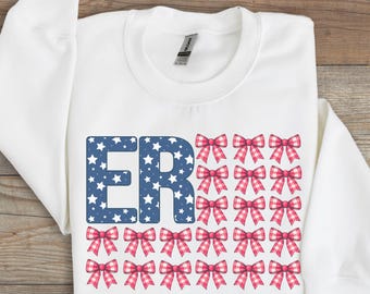 May include: White sweatshirt with a blue and white "ER" graphic and a red, white, and blue bow pattern. The graphic is in the style of an American flag.