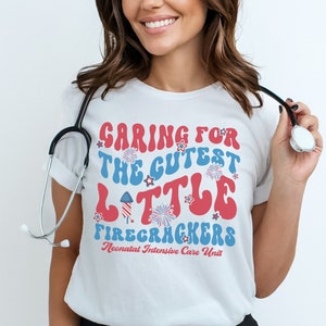 May include: White t-shirt with a red, white, and blue graphic that says "Caring for the Cutest Little Firecrackers Neonatal Intensive Care Unit".