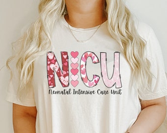 May include: A white t-shirt with a pink and red heart design that spells out "NICU" and the text "Neonatal Intensive Care Unit".