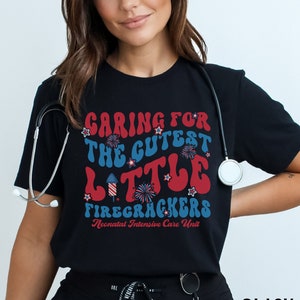 May include: Black t-shirt with a red, white, and blue graphic that says "Caring for the cutest little firecrackers Neonatal Intensive Care Unit".